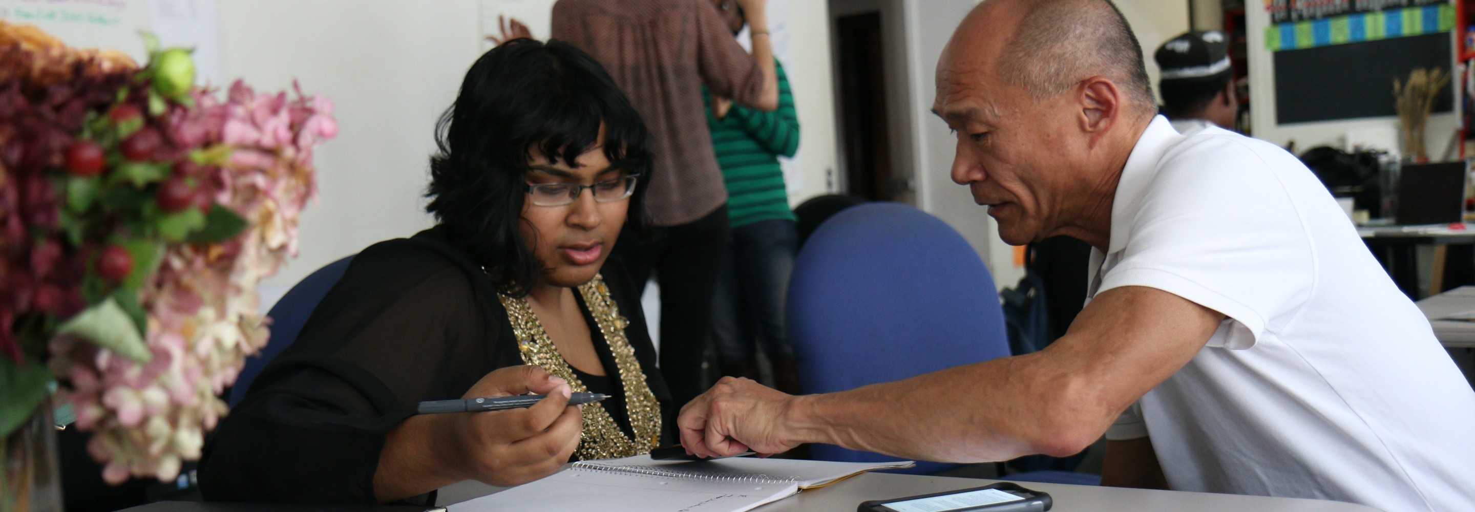 Two people are filling out a form together in a community center; Photo by Monica Melton on Unsplash