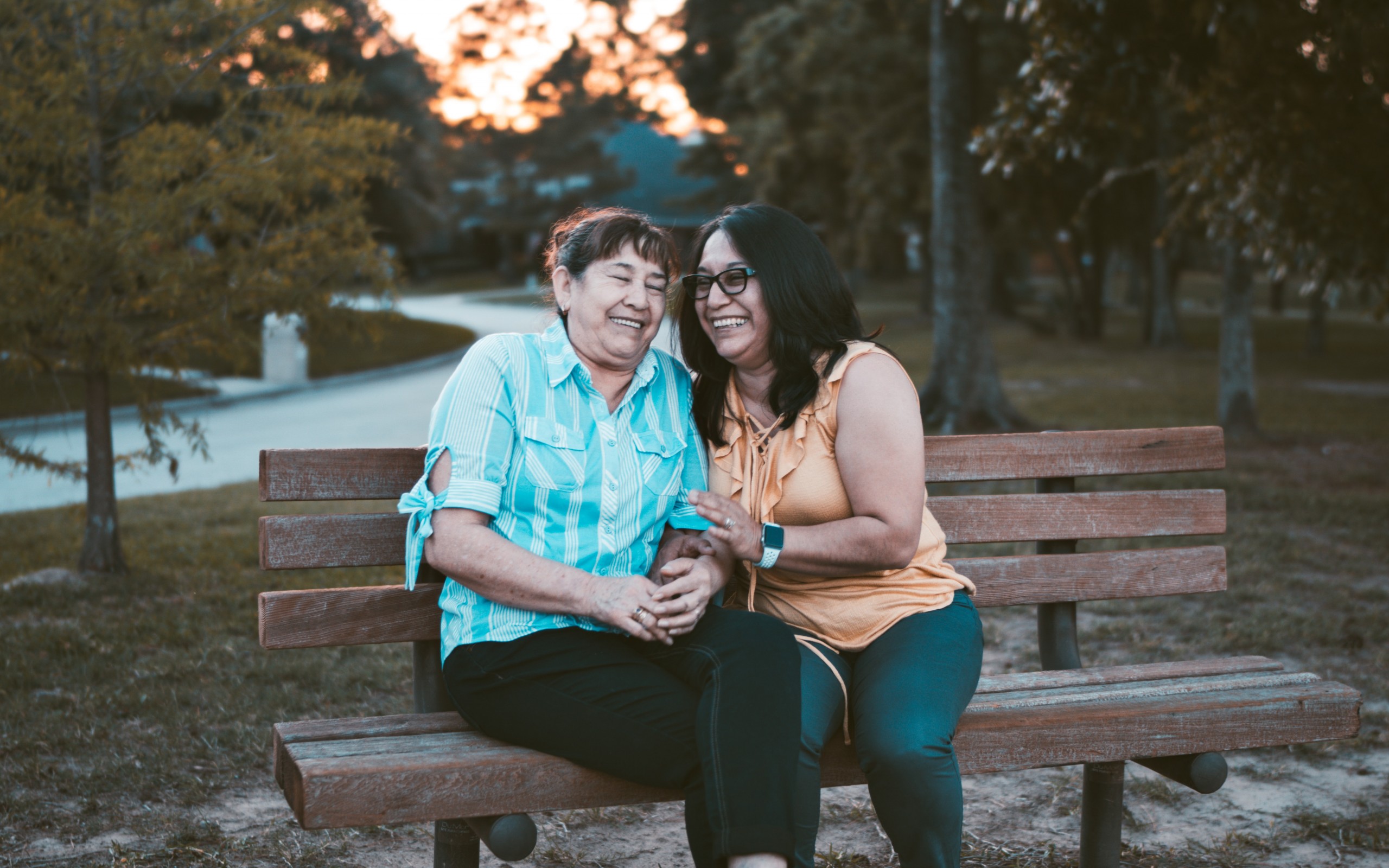 Two woman sitting on a bench smiling