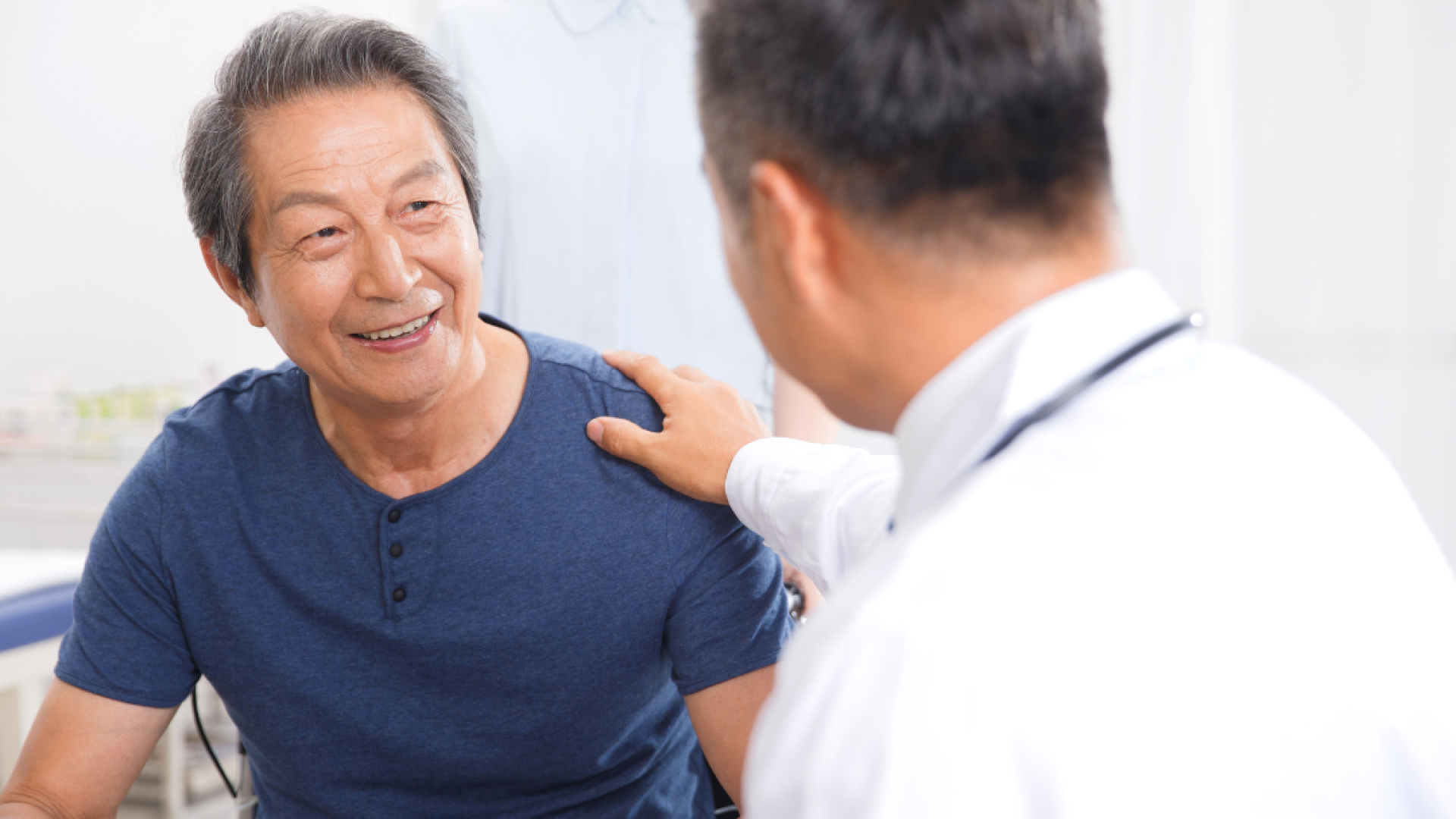 A doctor puts his hand on a man's shoulder