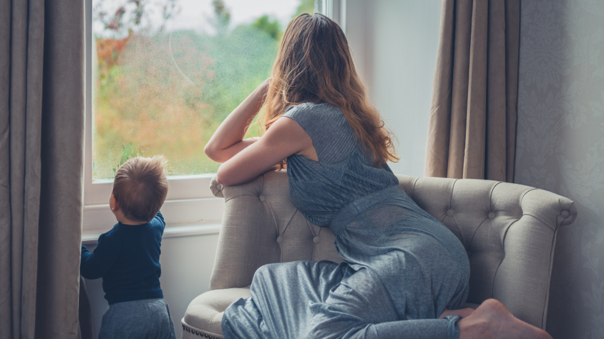 A woman and her toddler look out the window