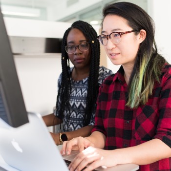 Two people typing at a computer together; Photo by Christina @ wocintechchat.com on Unsplash