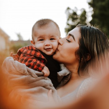 Woman kissing a smiling baby on the cheek; Photo by Omar Lopez on Unsplash