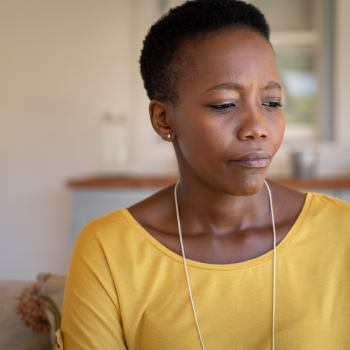 A woman in a yellow shirt frowns